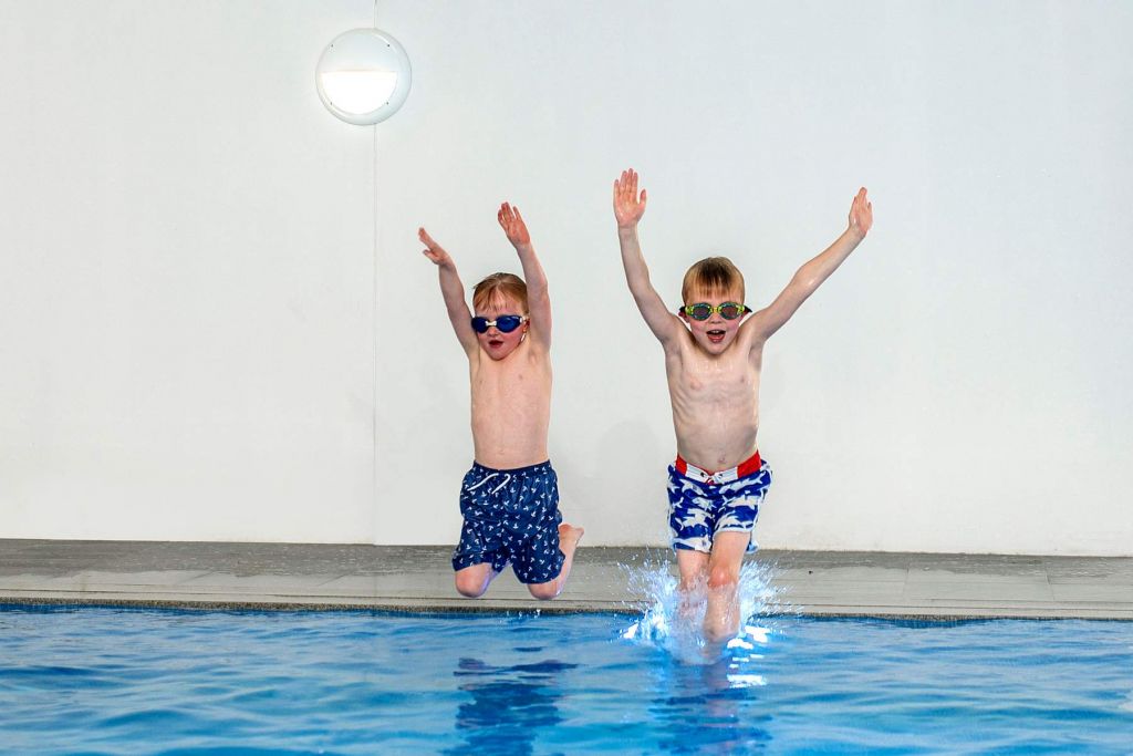 Two boys jumping into our swimming pool at our holiday houses in Hampshire