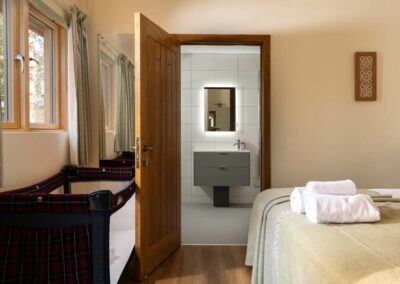 Double bedroom with travel cot and en-suite shower room at Portuguese Laurel holiday house in Hampshire